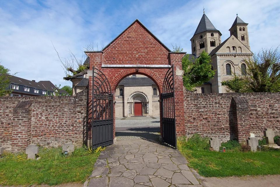 Blick durch das Eingangstor zum Friedhof auf das Seitenportal der Basilika